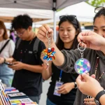 Custom keychains displayed at vibrant market stall with shoppers exploring unique designs and personalisation.